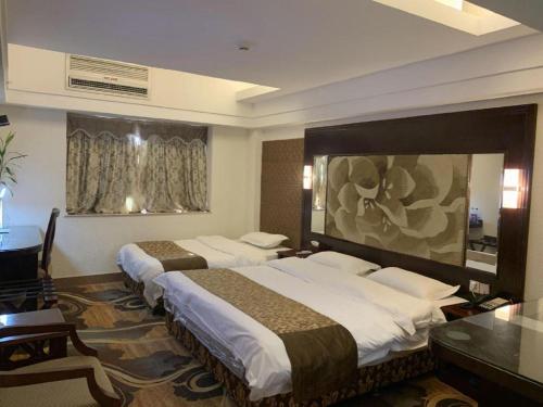 une chambre d'hôtel avec deux lits et un bureau dans l'établissement Oliva Hotel Shunde, à Shunde