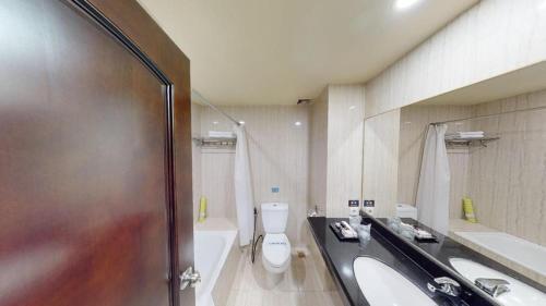 a bathroom with a toilet and a sink and a tub at Narita Classic Hotel in Tangerang