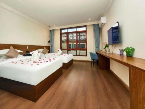 a hotel room with two beds and a desk at Lijiang Liwang Hotel in Lijiang