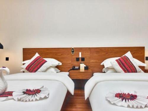 two beds in a hotel room with white sheets at Lijiang Liwang Hotel in Lijiang