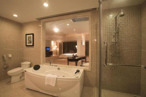 a bathroom with a tub and a toilet and a shower at Country Garden Phoenix Hotel Chizhou Jiuhua Mountain in Chizhou
