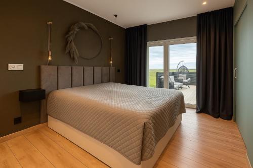 a bedroom with a large bed and a balcony at Mói Byggðarhorn in Selfoss