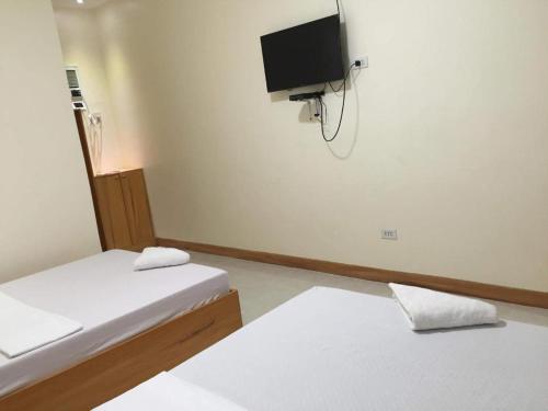 a room with two beds and a tv on the wall at Joaquim's Lodge in Luka