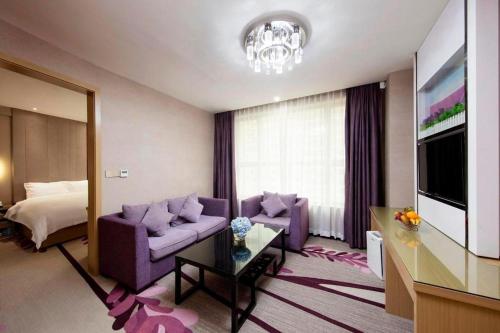 a living room with a purple couch and a bed at Lavande Hotels·Qingyuan Jinbiwan in Qingyuan