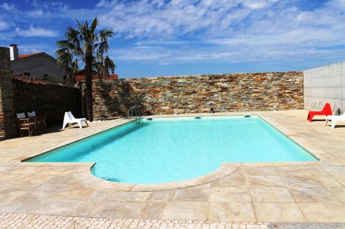 a swimming pool with two chairs and a brick wall at Casal da Porta - Quinta da Porta in Mirandela