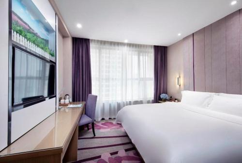 a hotel room with a large bed and a tv at Lavande Hotels·Qingyuan Jinbiwan in Qingyuan