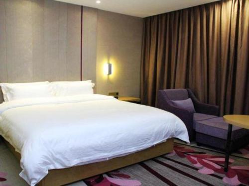 a bedroom with a large white bed and a chair at Lavande Hotels·Qingyuan Jinbiwan in Qingyuan
