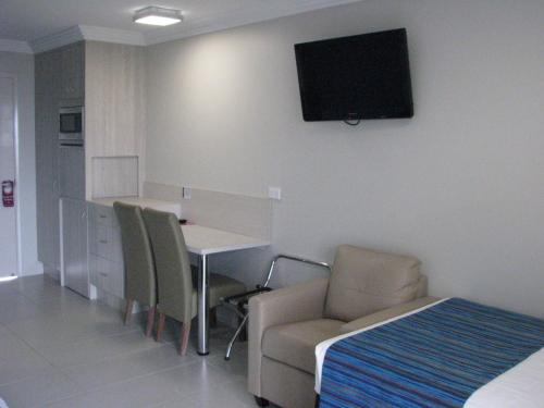 a room with a table and chairs and a television on the wall at Cardwell Beachcomber Motel & Tourist Park in Cardwell