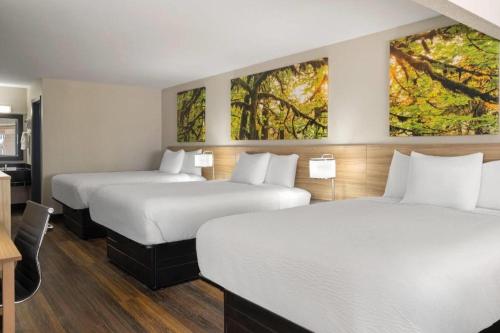 two beds in a hotel room with paintings on the walls at Days Inn & Suites by Wyndham Byram in Byram