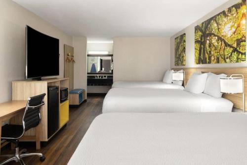 a hotel room with two beds and a flat screen tv at Days Inn & Suites by Wyndham Byram in Byram