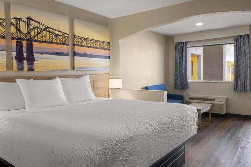 a bedroom with a bed and a bridge painting at Days Inn & Suites by Wyndham Byram in Byram