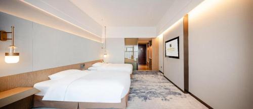 a bedroom with a large white bed and a hallway at Grand Metropark Hotel Chongqing in Chongqing