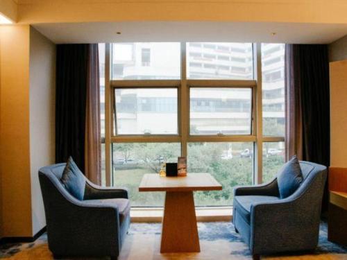 a living room with two chairs and a table and a window at Grand Metropark Hotel Chongqing in Chongqing