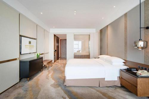 a bedroom with a large white bed and a desk at Grand Metropark Hotel Chongqing in Chongqing