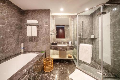 a bathroom with a tub and a sink at Grand Metropark Hotel Chongqing in Chongqing