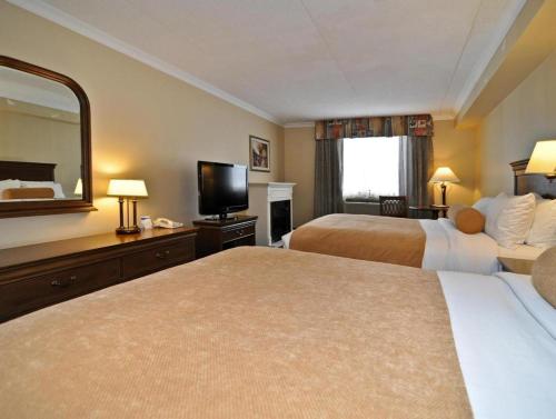 a hotel room with two beds and a large mirror at Best Western Plus Orillia Hotel in Orillia