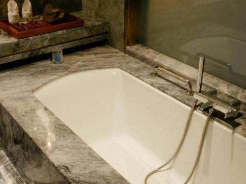 a white bath tub in a bathroom with a sink at Grand Metropark Hotel Chongqing in Chongqing