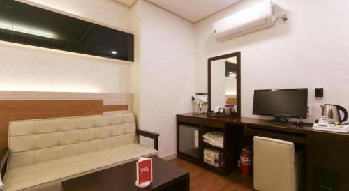 a room with a tv and a couch and a mirror at H Hotel in Ulsan