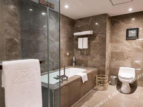 a bathroom with a tub and a toilet and a shower at Grand Metropark Hotel Chongqing in Chongqing