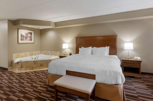 a hotel room with a large bed and a bath tub at Best Western Plus Orillia Hotel in Orillia