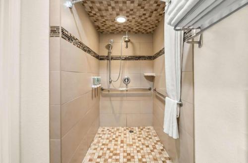 a bathroom with a shower with a tiled floor at Best Western Executive Inn in Los Banos
