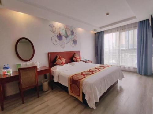 a bedroom with a bed and a desk and a mirror at GreenTree Inn Suzhou Shengze Hotel in Suzhou