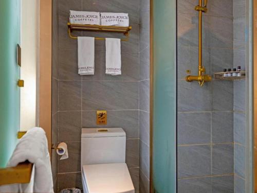 a bathroom with a toilet and a shower with towels at James Joyce Coffetel Xi'an Lingtong The Terracotta Army Huaqingchi University Town Metro Station in Xi'an