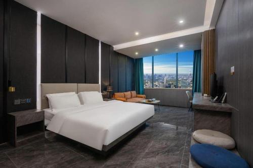 a bedroom with a large white bed and a living room at Haikou Kai Wei Hotel in Haikou