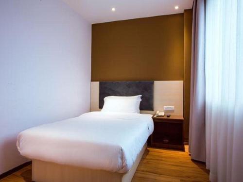 a bedroom with a large white bed and a window at JTOUR Inn Guilin Two Rivers and Four Lakes Walmart in Guilin
