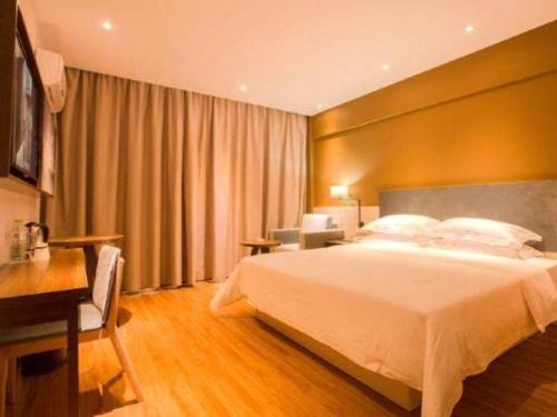 a hotel room with a large bed and a desk at JTOUR Inn Guilin Two Rivers and Four Lakes Walmart in Guilin