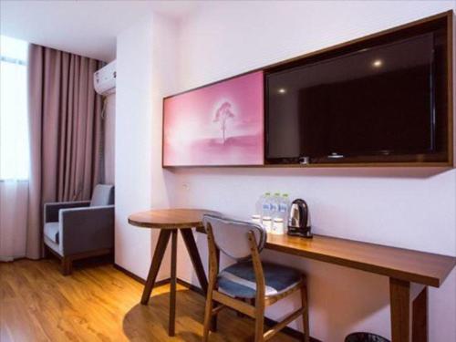 a hotel room with a desk and a flat screen tv at JTOUR Inn Guilin Two Rivers and Four Lakes Walmart in Guilin