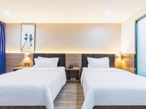 two beds in a hotel room with white sheets at 7 Days Inn Tianjin Development Zone 3rd Street Wanli in Binhai