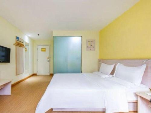 a large white bed in a room with yellow walls at 7 Days Inn Tianjin Development Zone 3rd Street Wanli in Binhai