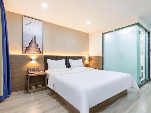 a bedroom with a large white bed and a window at 7 Days Inn Tianjin Development Zone 3rd Street Wanli in Binhai