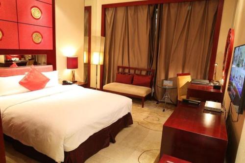 a hotel room with a large bed and a desk at Dunhuang Grand Soluxe Hotel in Dunhuang