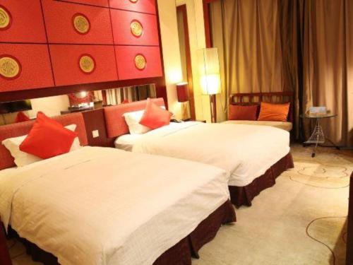 two beds in a hotel room with red walls at Dunhuang Grand Soluxe Hotel in Dunhuang