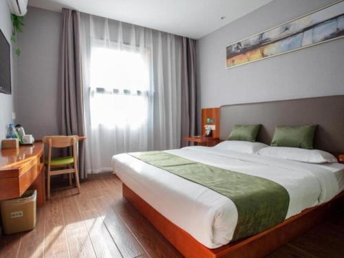 a bedroom with a large bed with a desk and a window at Vatica Shanghai Jiading District Anting Metro Station Moyu Road Hotel in Shanghai