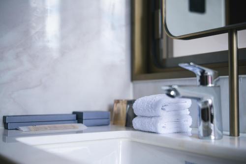 a bathroom sink with towels and a mirror at Hotel Benito in Hong Kong
