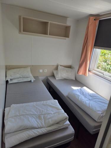 deux lits dans une petite pièce avec une fenêtre dans l'établissement Mobil-home - 8pers - 10m des piscines, à Gastes