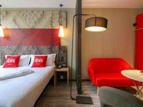 a hotel room with a bed and a red chair at ibis xian North Second Ring Weiyang Rd Hotel in Xi'an