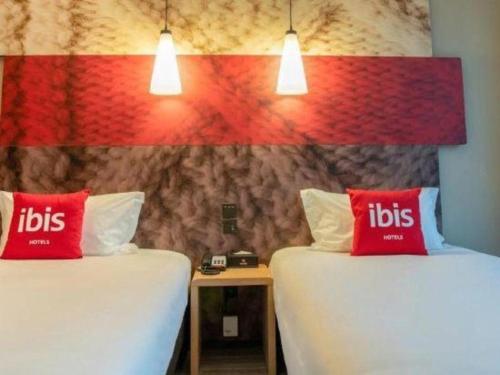 two beds with red pillows in a room at ibis xian North Second Ring Weiyang Rd Hotel in Xi'an