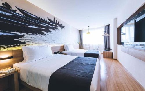 a hotel room with two beds and a painting on the wall at Ibis Styles Shanghai Qingpu Sports Center Hotel in Shanghai