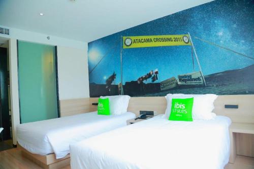 two beds in a hotel room with a sign on the wall at Ibis Styles Shanghai Qingpu Sports Center Hotel in Shanghai