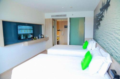 a bedroom with two beds with green pillows at Ibis Styles Shanghai Qingpu Sports Center Hotel in Shanghai