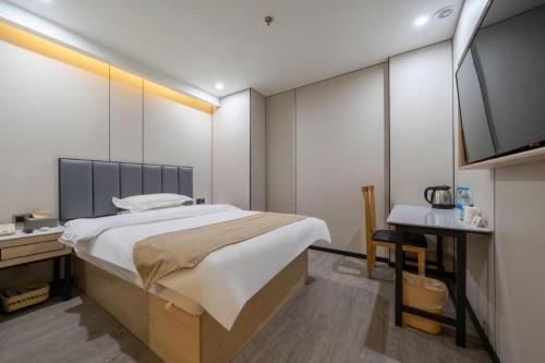 a bedroom with a large bed and a flat screen tv at GreenTree Inn Shanghai Railway Station Macao Road in Shanghai