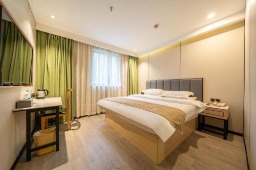 a large bedroom with a large bed and a desk at GreenTree Inn Shanghai Railway Station Macao Road in Shanghai