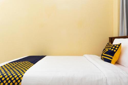 a bed with two yellow and blue pillows on it at SPOT ON 2063 Bethania Residence in Kupang