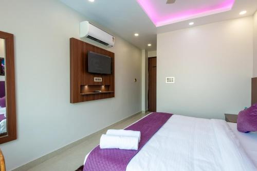 a bedroom with a bed and a tv on the wall at Hotel Purple Dot Haridwar in Haridwār