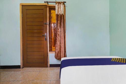 a room with two beds and a door with a window at SPOT ON 91159 Kost Putrana Syariah in Bandung