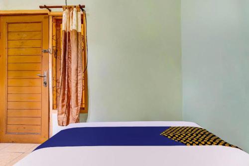 a bedroom with a bed and a wooden cabinet at SPOT ON 91159 Kost Putrana Syariah in Bandung